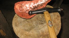 Feinarbeit mit Eisenhammer auf Holzklotz